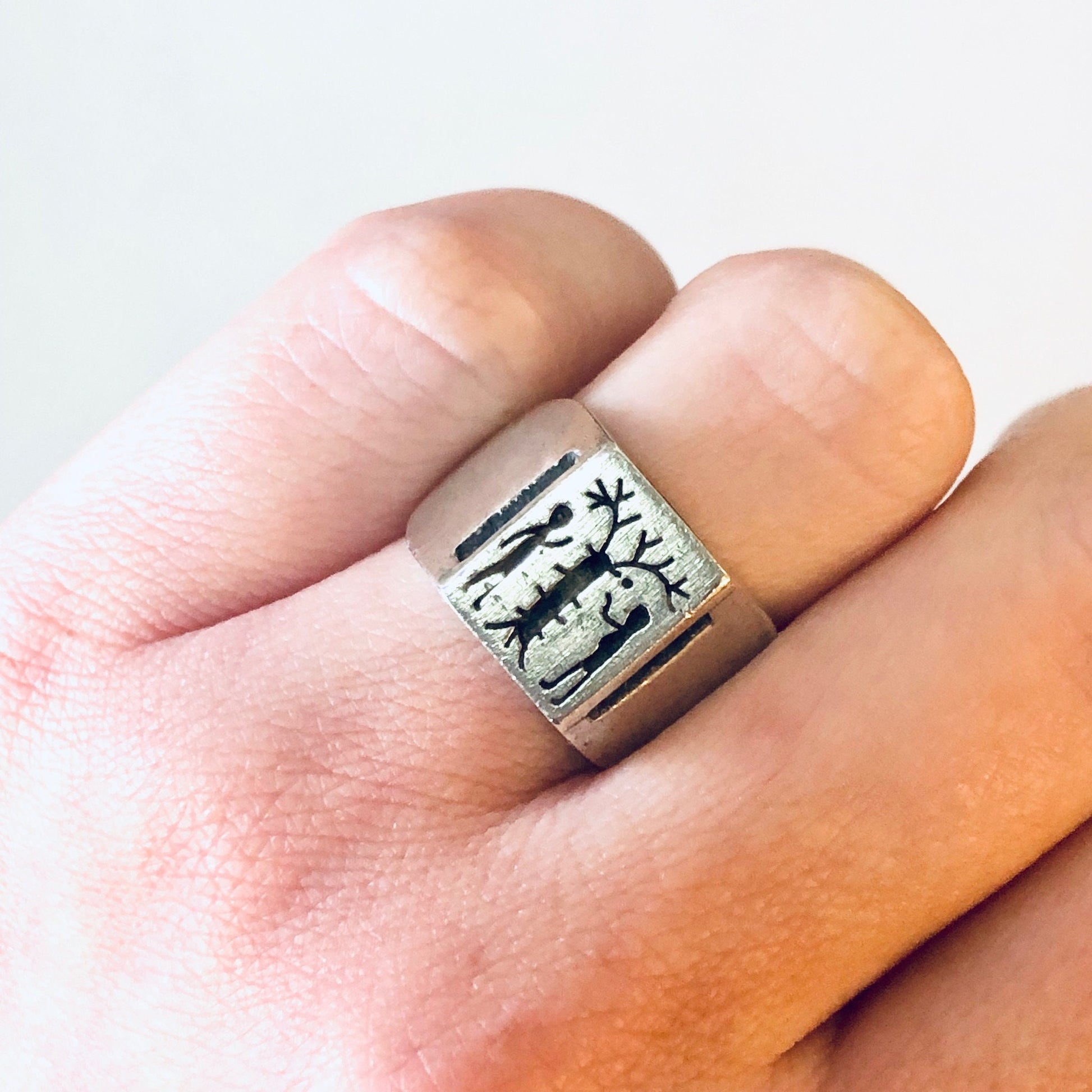 Vintage silver Adam and Eve tree of life ring on a finger, depicting the Biblical story of forbidden fruit. Unique religious jewelry from 925 sterling silver.