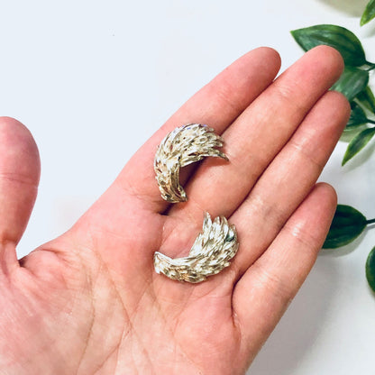 Vintage silver feather or leaf-shaped earrings held in palm of hand