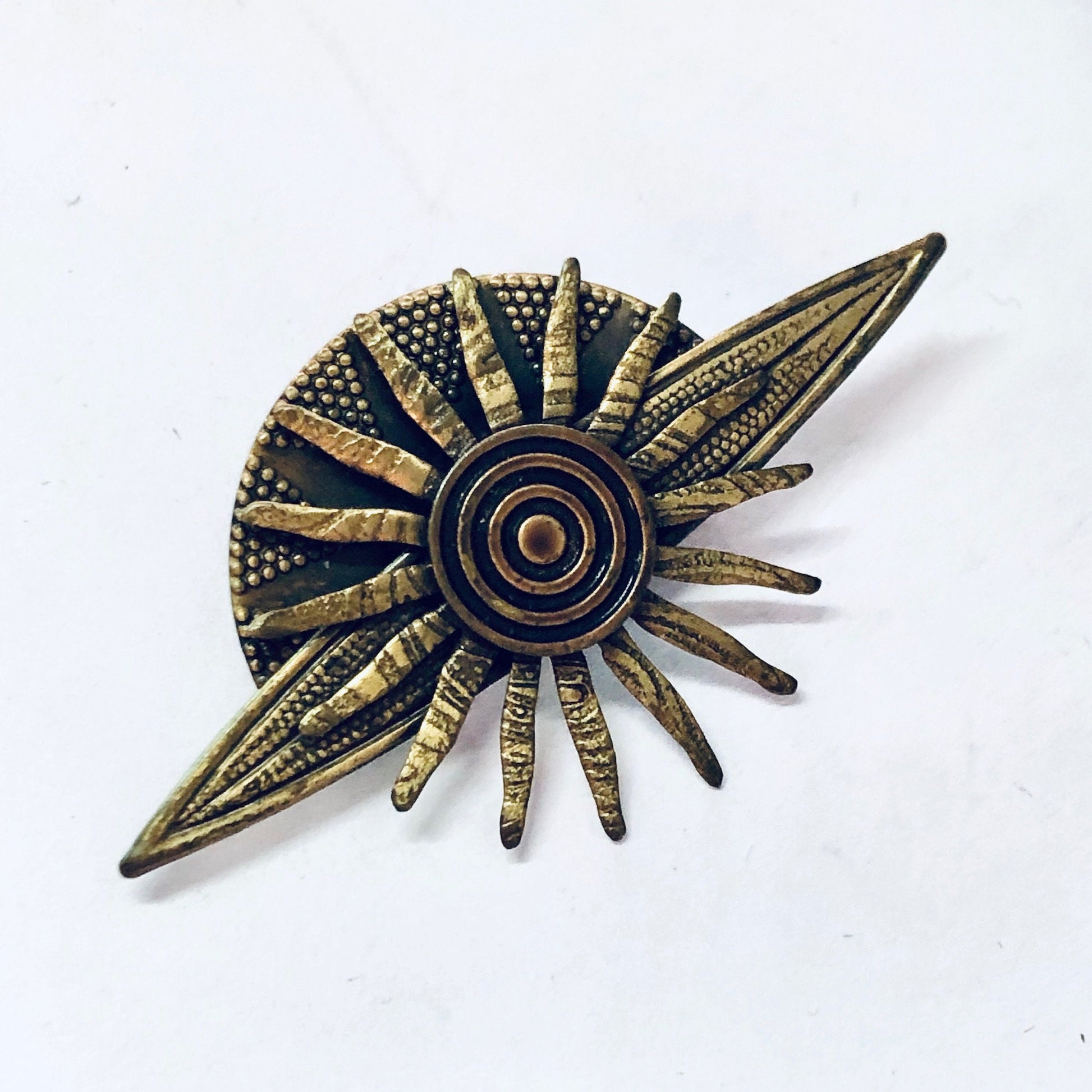 Vintage brass-toned sun brooch pin with intricate details resembling a solar system or planet, perfect as costume jewelry or a unique gift idea.