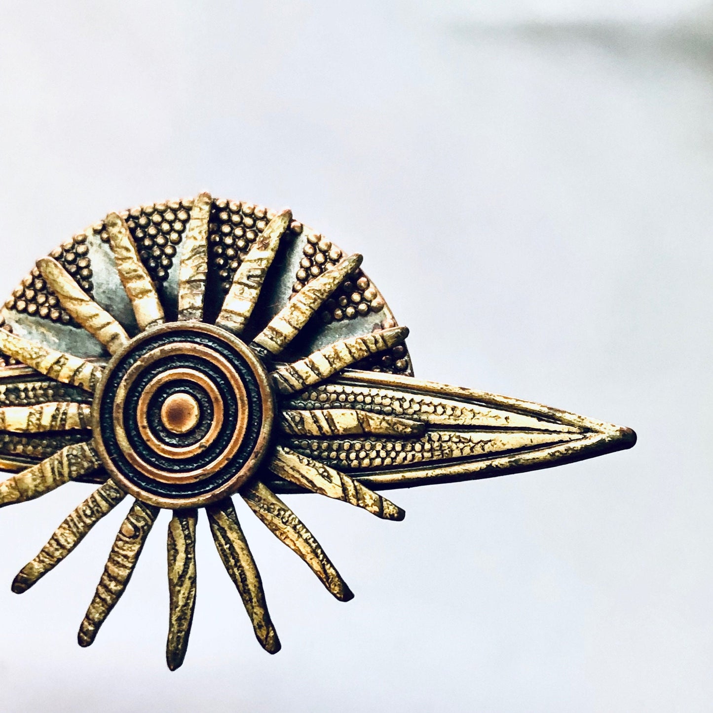 Vintage brass sun-shaped brooch with textured rays and central circle design, resembling a celestial body or planet from the solar system, suitable as unique costume jewelry gift.