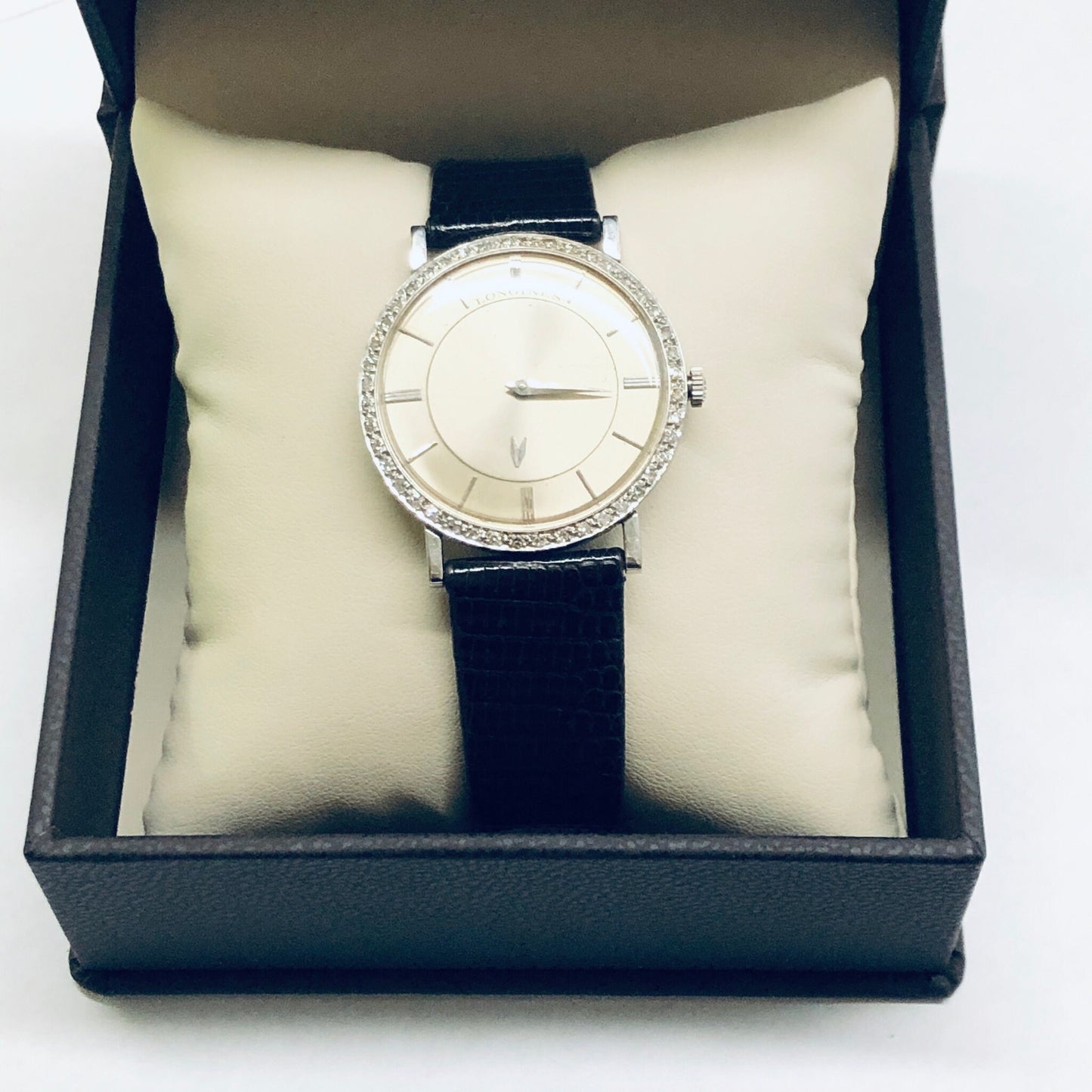 Vintage Longines mystery dial watch with 18K white gold case, diamond bezel, and black leather strap, presented in a gift box.