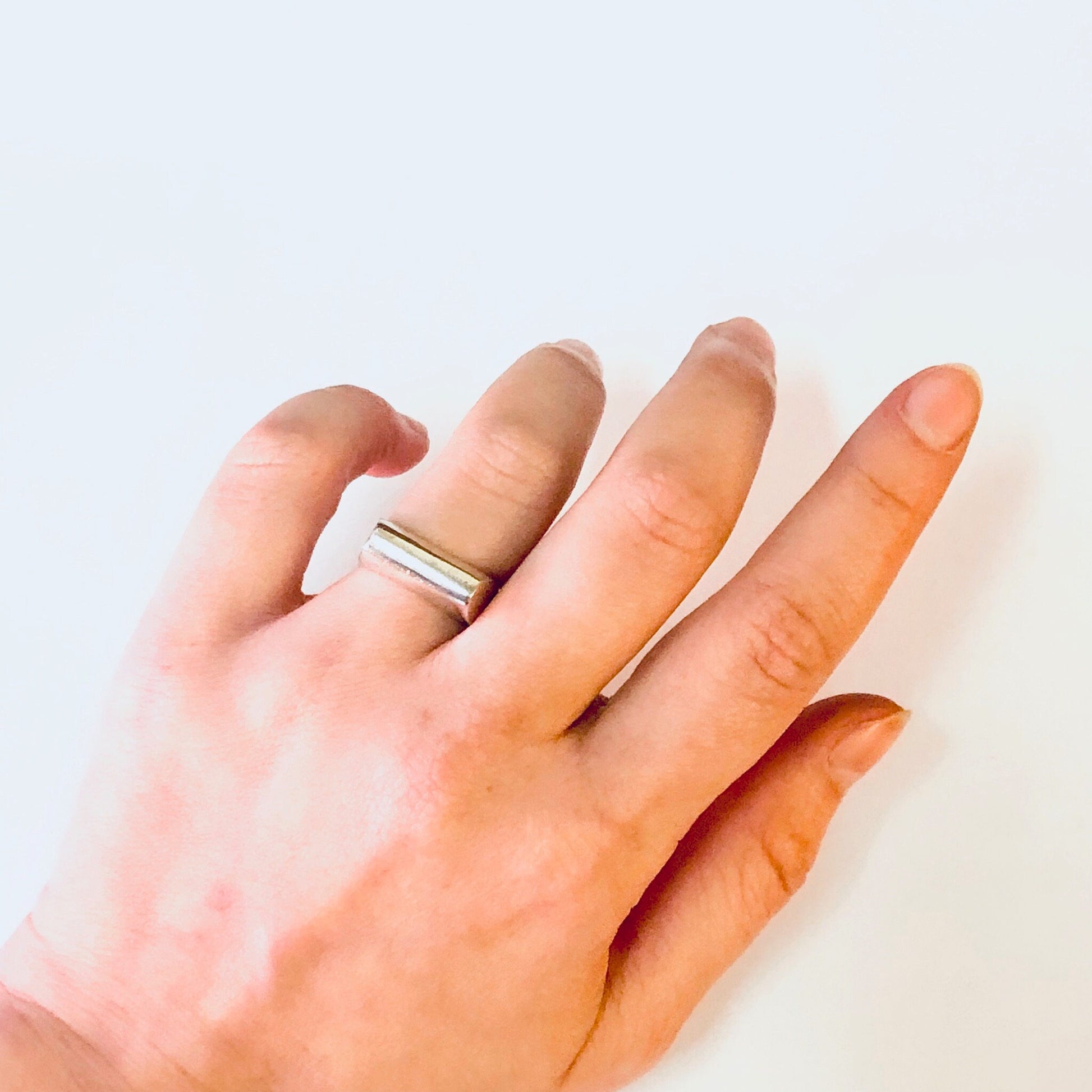 Vintage silver band ring on hand, simple modernist jewelry design, unique sleek 925 ring