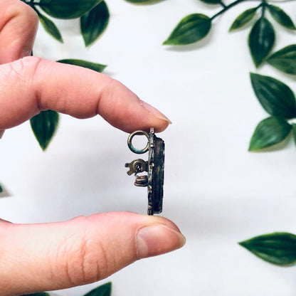 Vintage silver round pendant brooch necklace held in fingers against blurred green leaf background, unique 925 silver jewelry piece