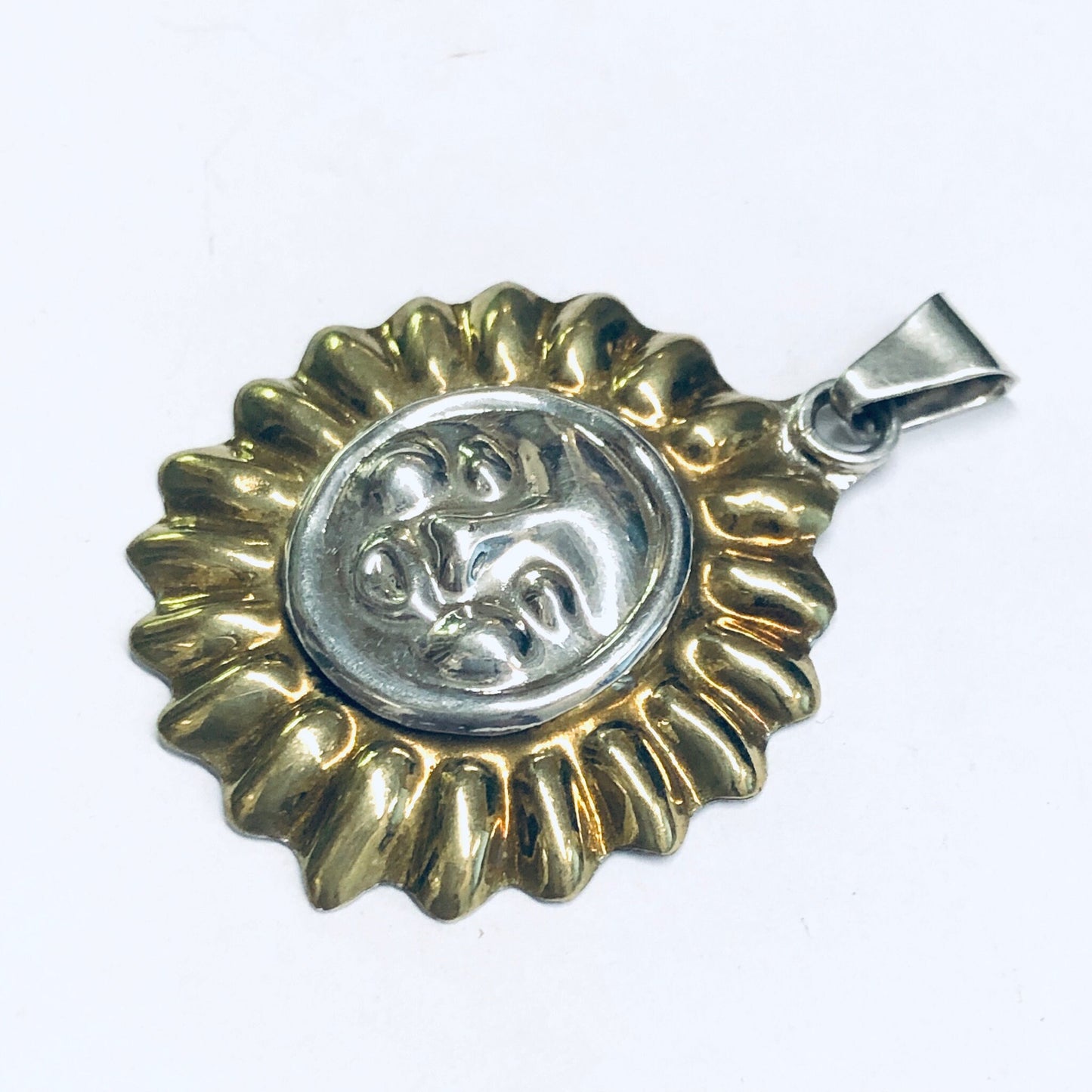 Vintage silver sun face pendant with gold accents and intricate details, suitable for a necklace or charm jewelry.