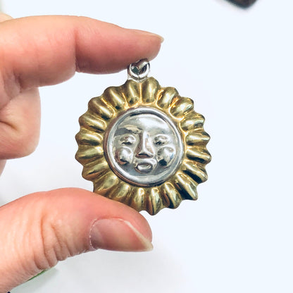 Vintage silver and gold sun face pendant charm held in fingers