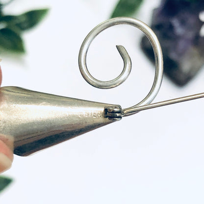 Silver calla lily brooch pin curled into spiral design on white background