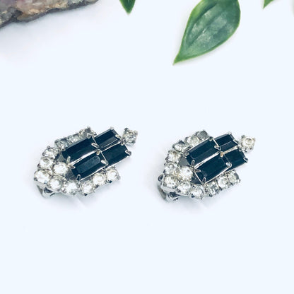 Elegant vintage-style clip-on earrings featuring black baguette rhinestones surrounded by round clear rhinestones, set in a silver tone metal.