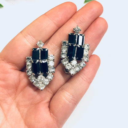 Vintage black and silver rhinestone clip-on earrings held in palm of hand