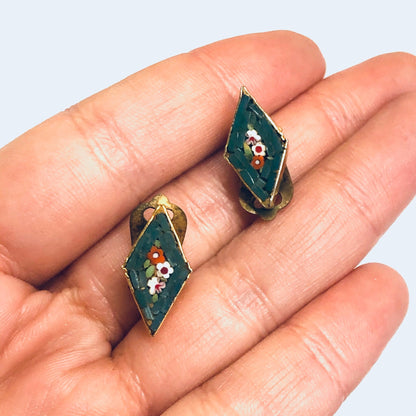 Vintage green mosaic millefiori clip-on earrings with floral design, held in hand against white background