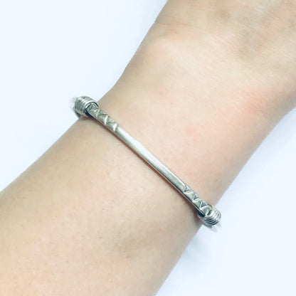 Vintage silver thin cuff bracelet on wrist, simple small silver cuff bracelet, close-up view of vintage silver jewelry worn on arm.