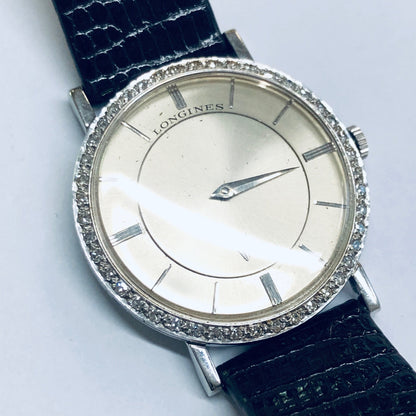 Vintage Longines mystery dial watch with 18K white gold case, diamond bezel, and silver dial on dark blue leather strap, working condition, suitable for men or women.