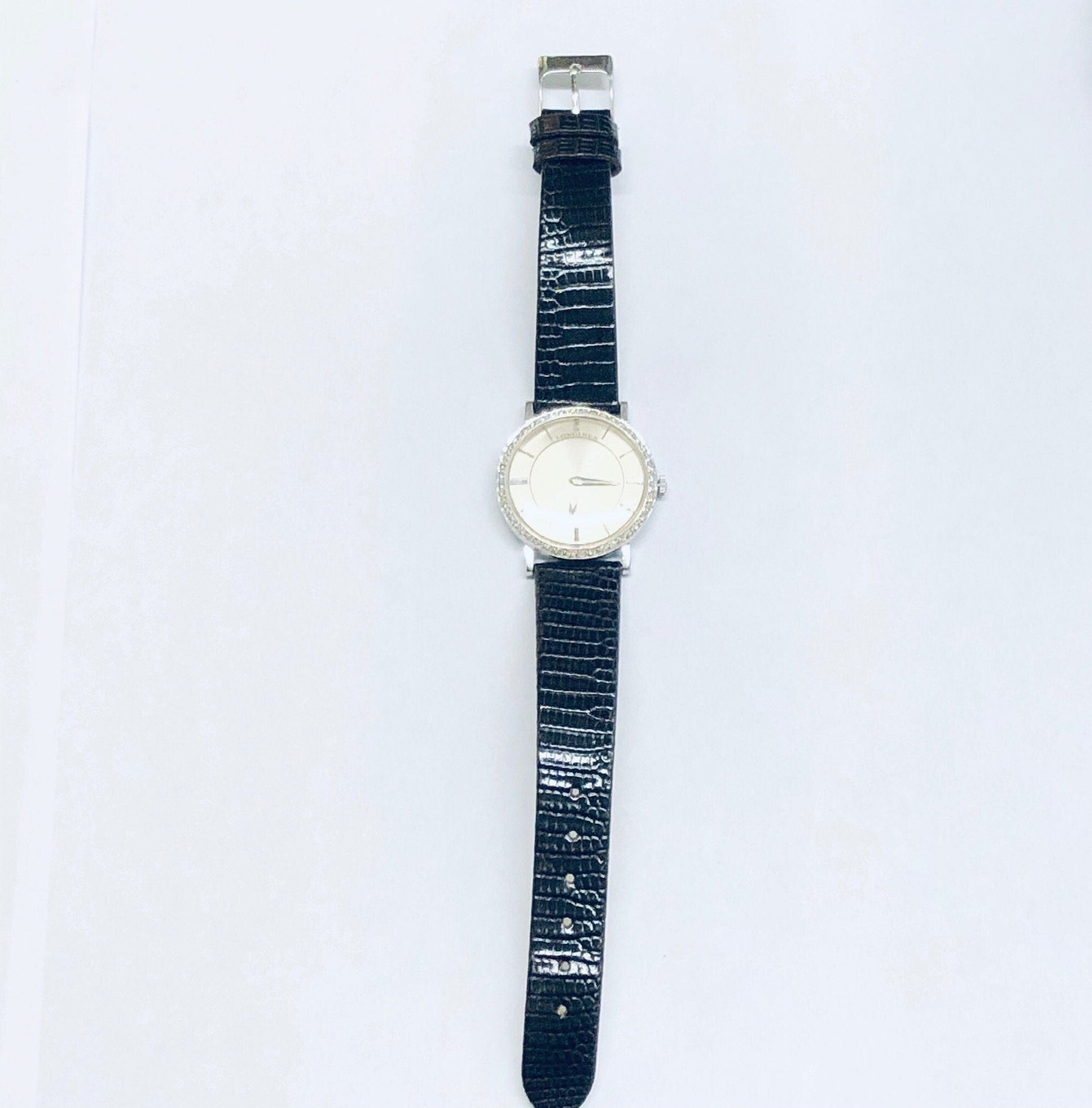 Vintage Longines mystery dial watch with 18K white gold case, diamond bezel, and blue leather strap