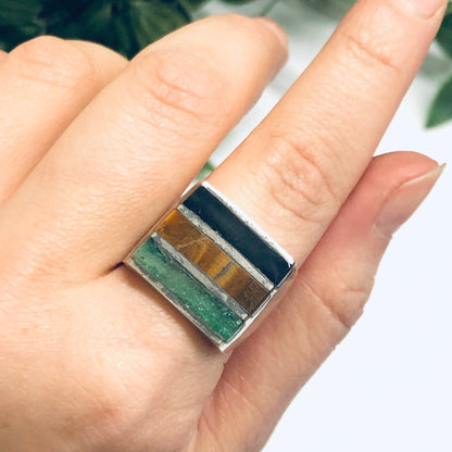 Silver ring with natural inlaid stones of black onyx, malachite and tiger's eye, worn on a finger, vintage men's jewelry