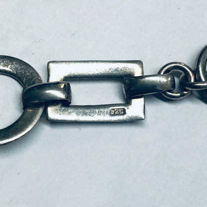 Vintage silver geometric link bracelet with circle and rectangle cutouts and toggle closure, close-up view on white background