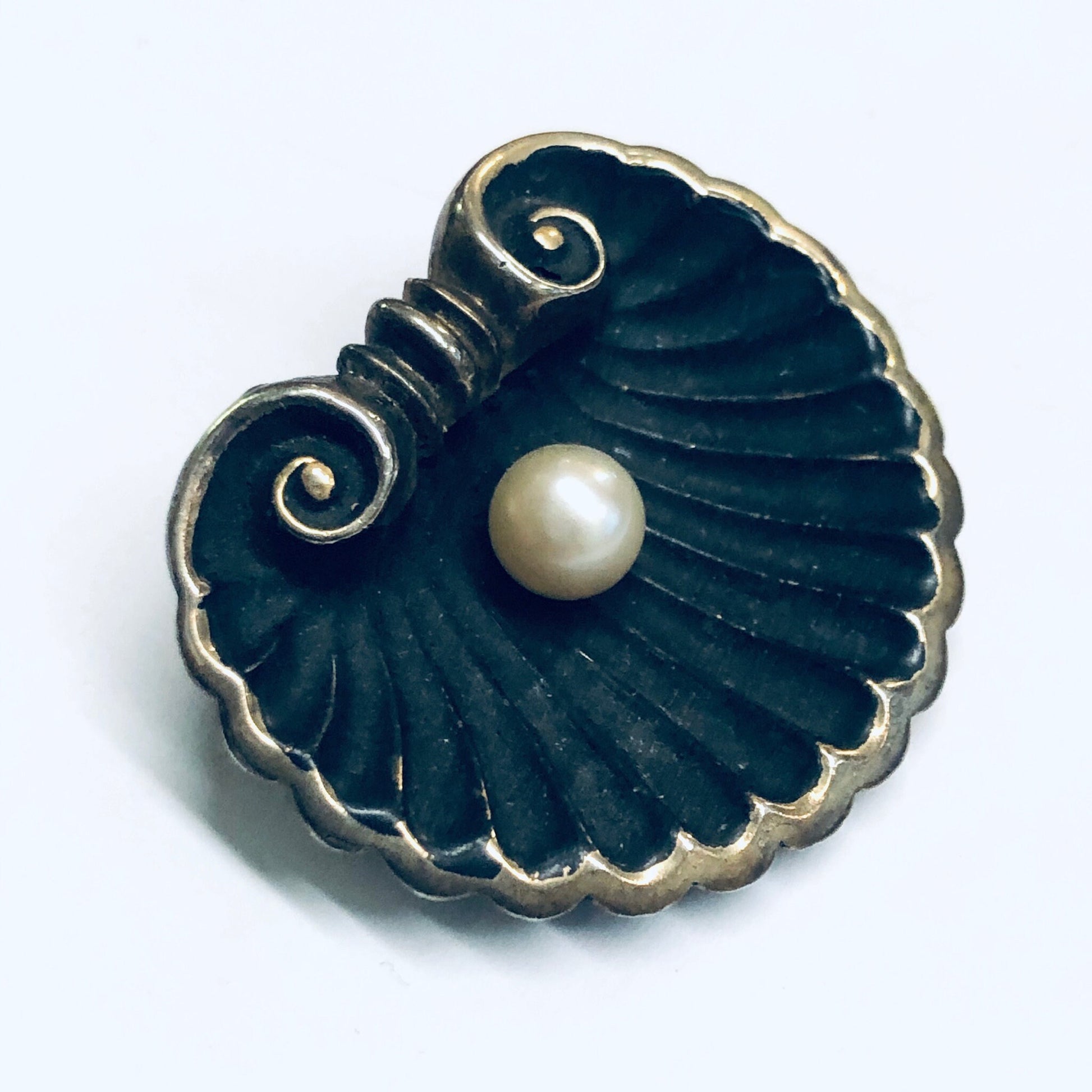 Antique gold-washed seashell brooch with matte black enamel and central pearl accent, in the Art Nouveau style.