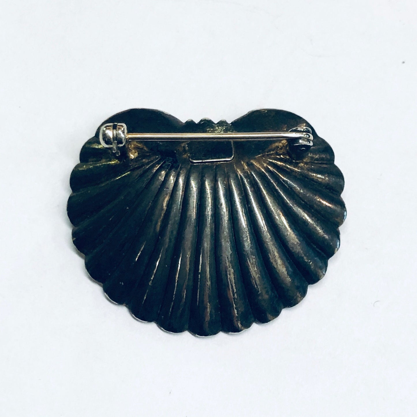 Vintage black seashell-shaped brooch with ribbed design and gold trim, likely sterling silver with pearl accent, in the Art Nouveau style.