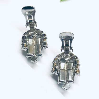 Vintage black rhinestone clip-on earrings with silver tone metal, featuring faceted stones in an art deco inspired design.