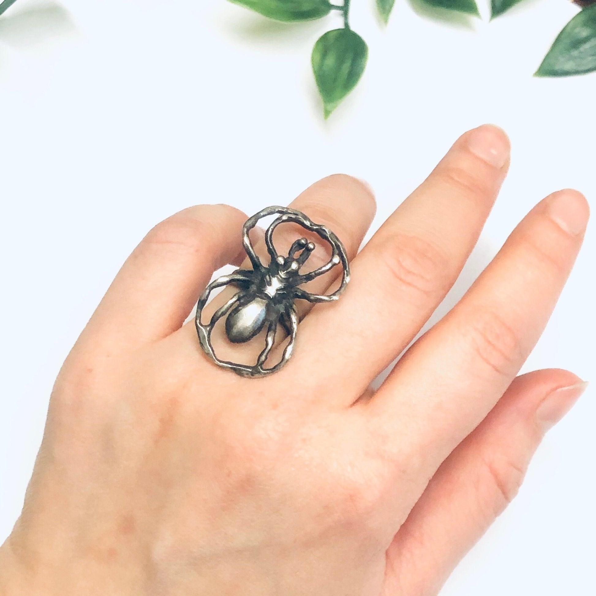 Silver spider ring worn on hand with leaves in background