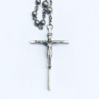 Silver rosary prayer beads with crucifix pendant on a white background, religious jewelry closeup