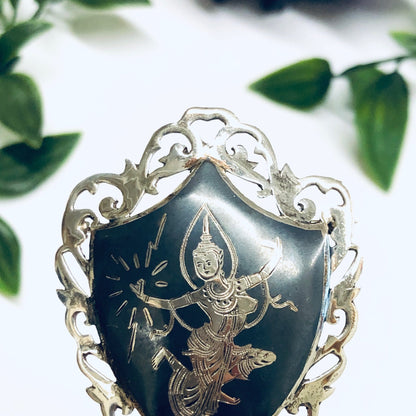 Vintage Siam sterling silver brooch depicting the goddess Mekkala, adorned with intricate engraved details and a dark blue enamel background, attributed to Amfarco, a renowned Thai silver jewelry maker.