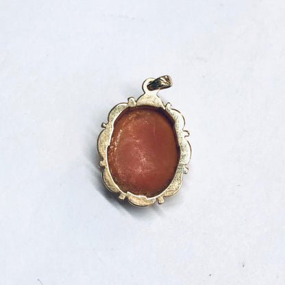 Vintage 14K gold cameo pendant featuring a small oval coral cameo set in an ornate yellow gold frame against a white background.