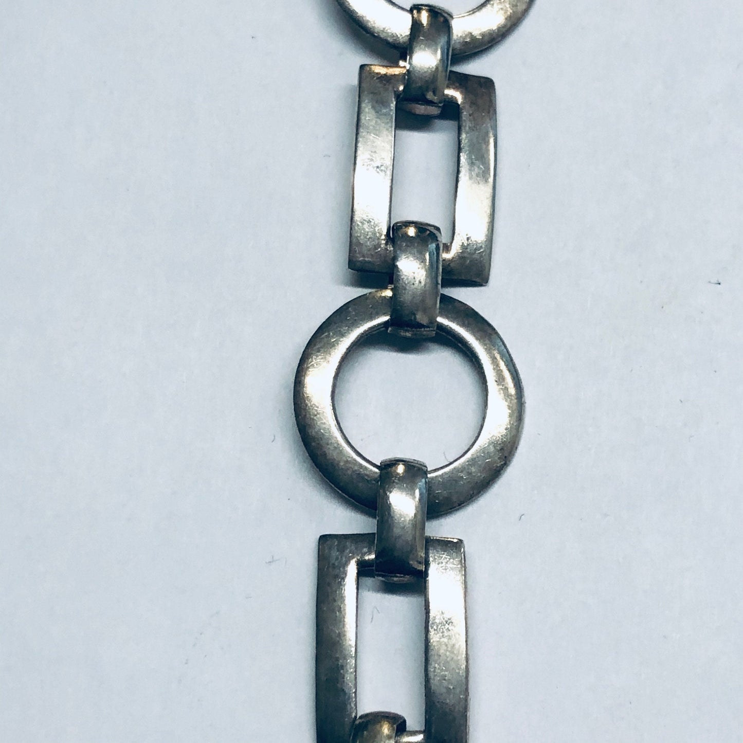 Geometric silver link bracelet with circle and rectangle cutouts, featuring a toggle clasp closure, vintage jewelry style.