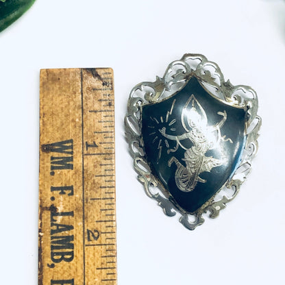 Antique Amfarco Siam sterling silver brooch depicting the goddess Mekkala, with an ornate shield-shaped frame and deep blue enamel background, shown next to a vintage wooden ruler for scale.