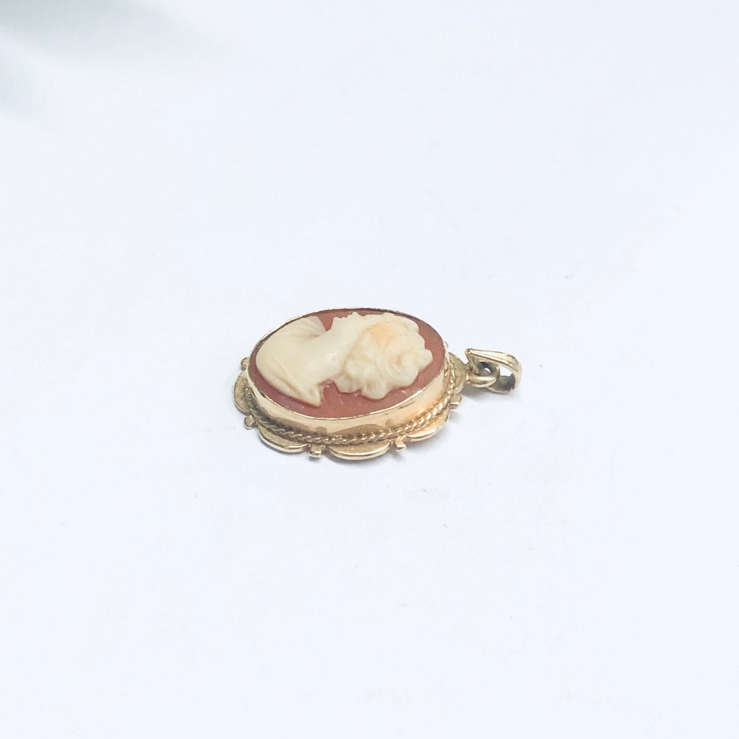 14K yellow gold vintage oval cameo pendant with delicate carved shell portrait against a plain white background.