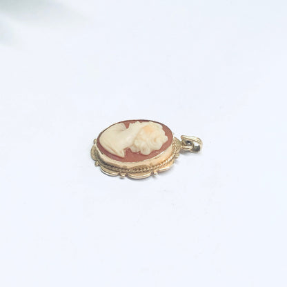 14K yellow gold vintage oval cameo pendant with delicate carved shell portrait against a plain white background.