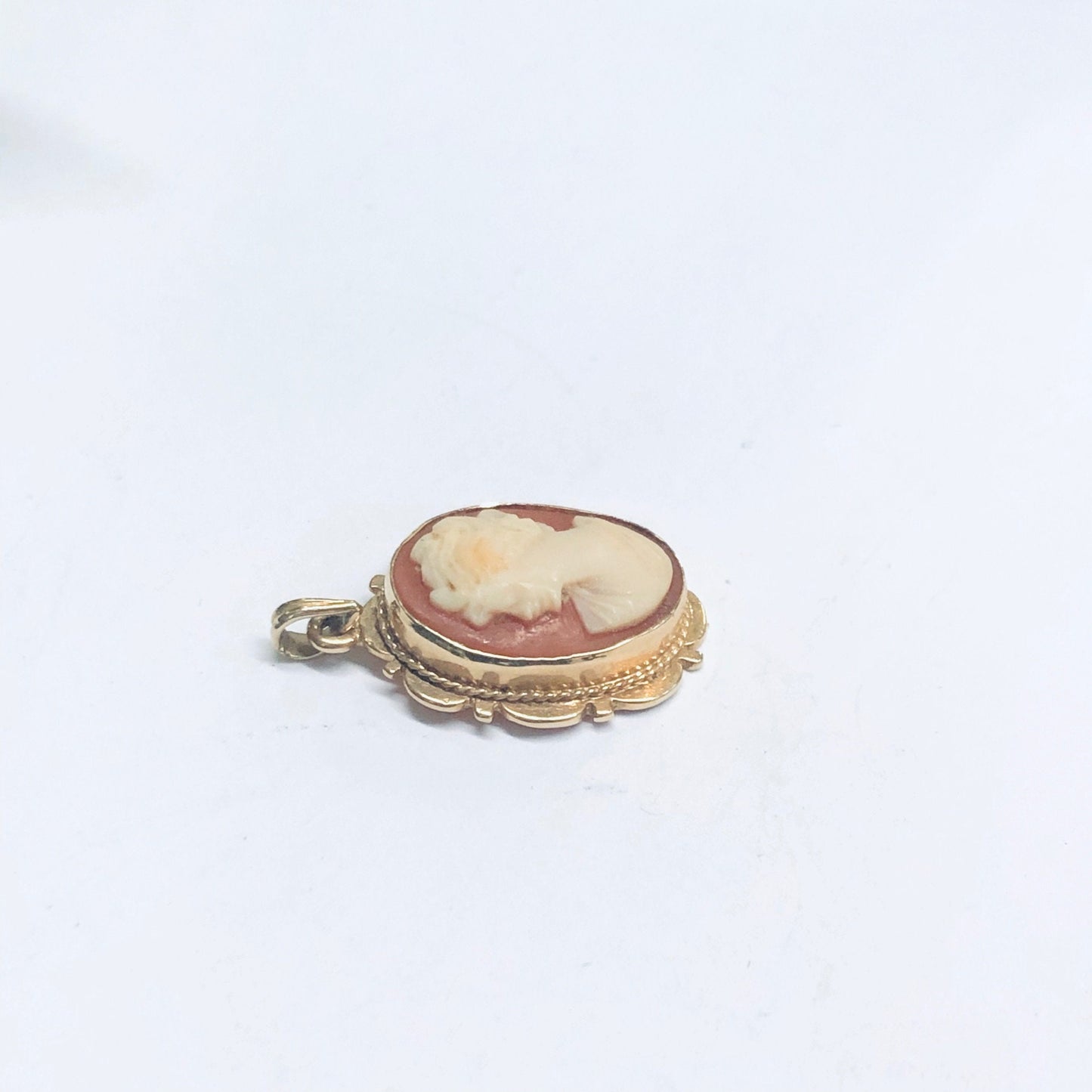 Vintage 14K gold cameo pendant featuring a small, oval-shaped cameo with a detailed profile carving set in an ornate yellow gold frame with scalloped edges and decorative accents, displayed on a white background.