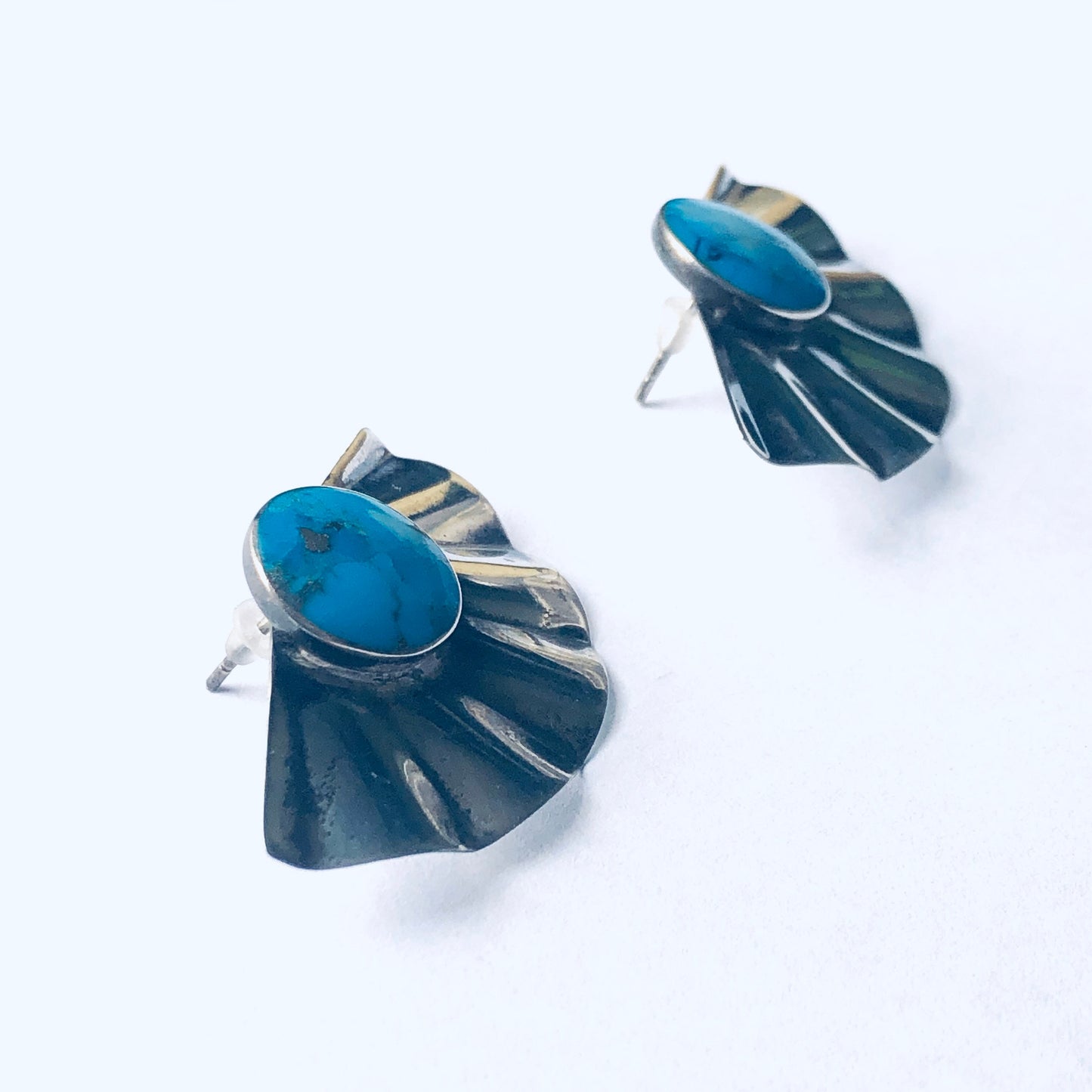 Vintage silver fan-shaped earrings with vivid blue gemstones, designed for pierced ears.