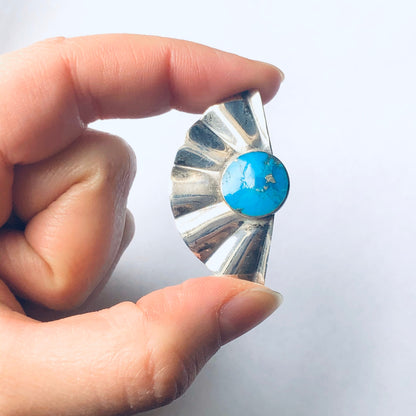 Vintage silver fan-shaped earrings with bright blue turquoise stone held in hand against white background