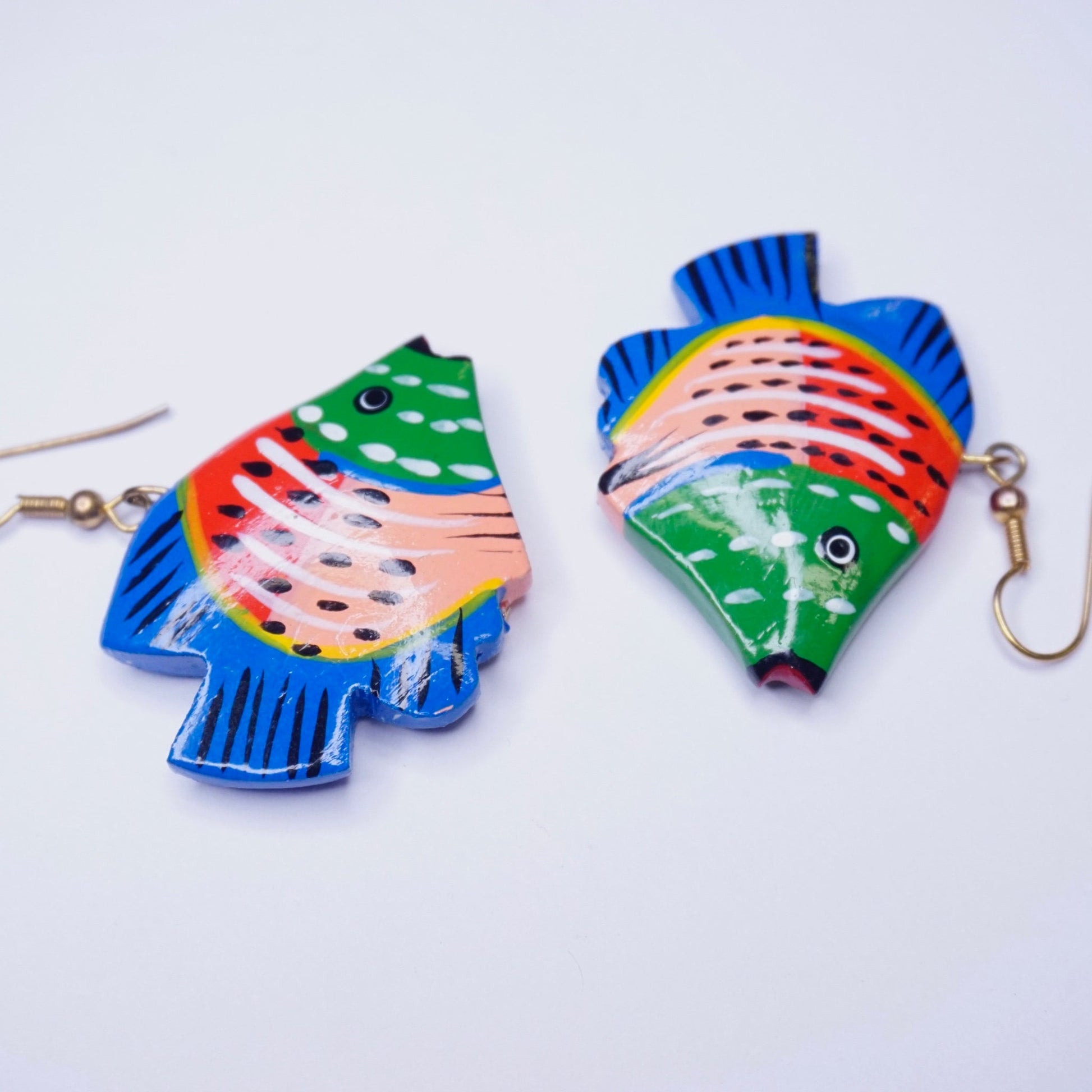 Alt text: Colorful vintage wood carved fish-shaped earrings with vibrant blue, green, pink, and white paint details on a white background, featuring gold-tone dangle hooks, handmade wooden statement earrings.