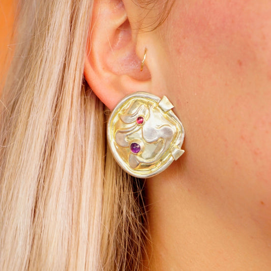 Vintage William and Shellie sterling silver abstract earrings with small amethyst gemstones, worn on a woman's ear with blonde hair