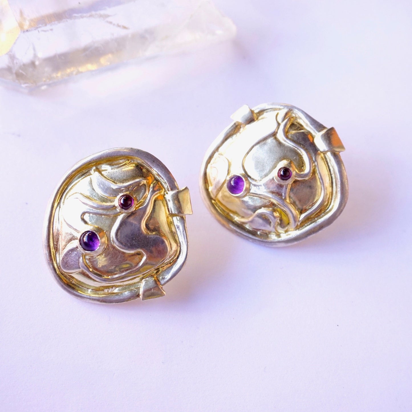 Vintage William and Shellie sterling silver abstract modernist earrings featuring small amethyst gemstones set into curved, sculptural designs against a soft purple background.