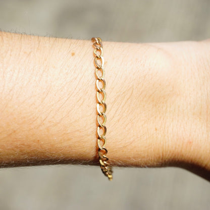 Delicate vintage 10K gold Cuban chain bracelet, 7 inches long, shown on wrist, close-up view highlighting intricate chain links and lustrous gold finish, minimalist design suitable for everyday wear or special occasions.