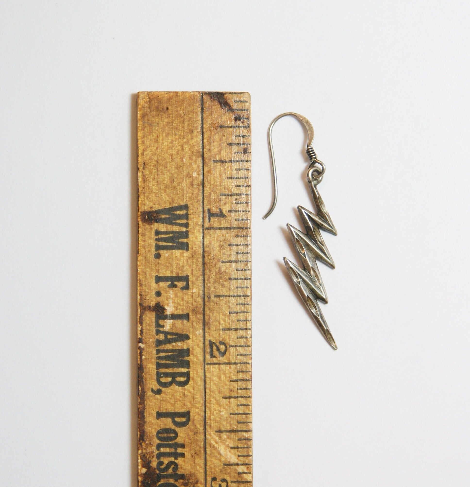 Vintage wooden ruler with sterling silver lightning bolt earrings on white background