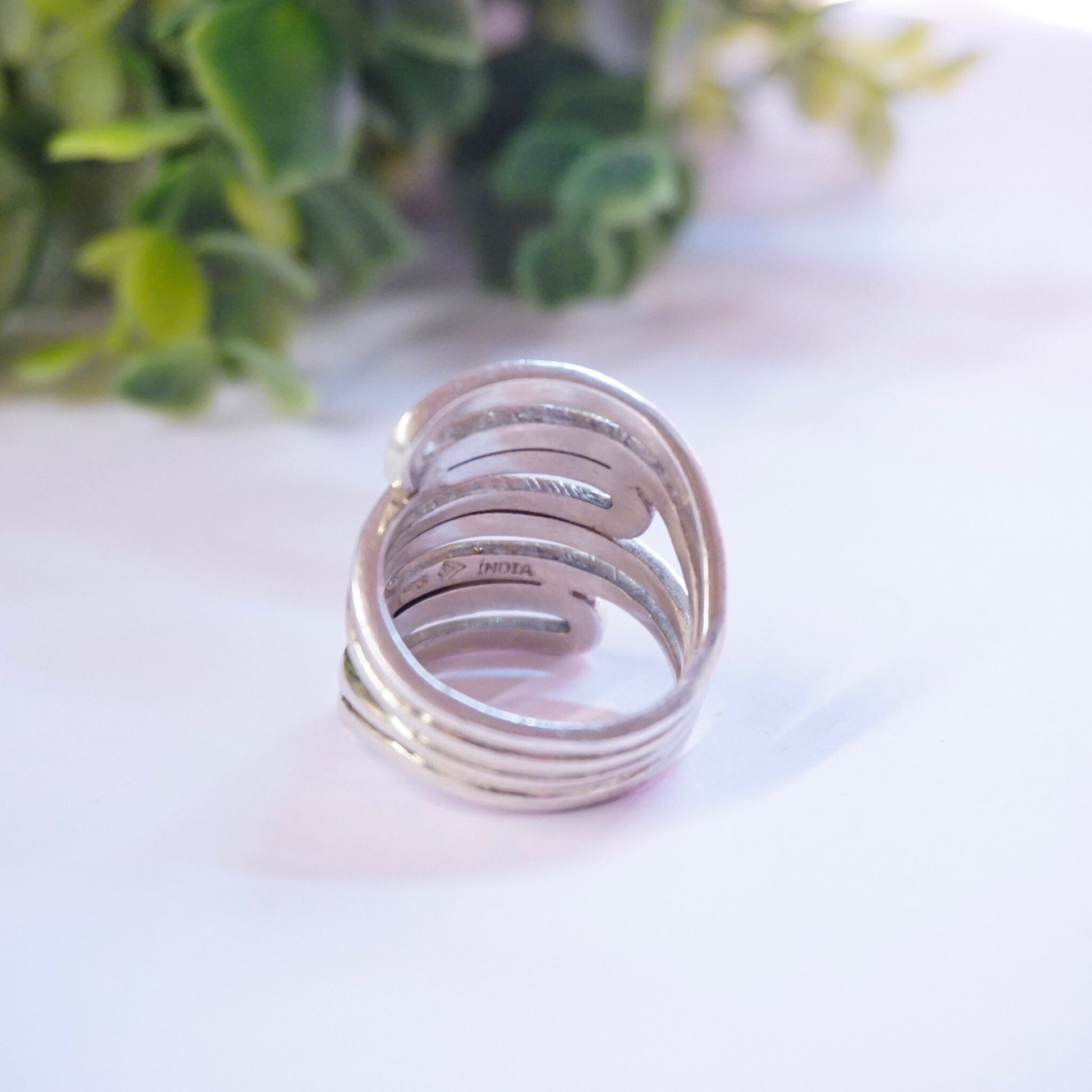 Vintage sterling silver cut-out ring with unique design, handmade in India, 925 silver statement jewelry piece displayed on white background with greenery behind.