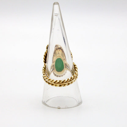 Vintage 14K gold cocktail ring with green jade center stone and diamond accent, featuring a twisted gold band design. Large jade stone set in a clear glass or plastic display cone.