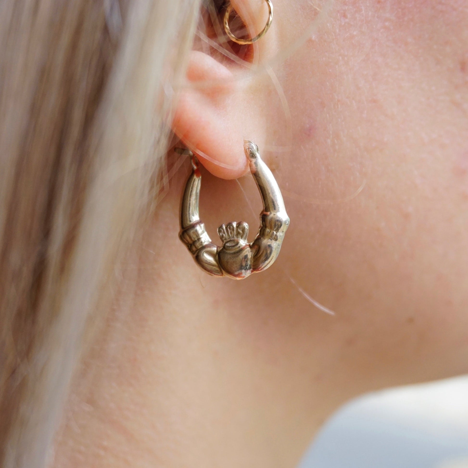Close-up of a woman wearing vintage sterling silver Claddagh hoop earrings, embodying the classic Irish symbol of love, loyalty, and friendship, crafted from 925 sterling silver jewelry.