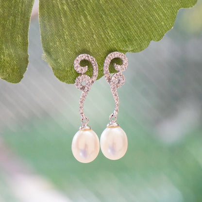 Vintage 14K white gold diamond and pearl drop earrings on green leaf, delicate pearl drop earrings with sparkling diamond accents on chain, elegant pearl and diamond stud earrings