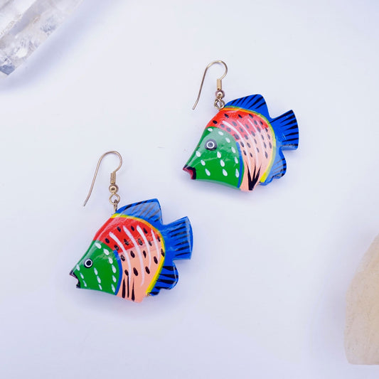 Colorful vintage wood carved fish earrings with blue, pink, and green paint details on a white background, handmade wooden dangle statement earrings.