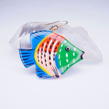 Alt text: Handmade vintage wood carved fish earrings with colorful painted design, featuring blue, orange, and green patterns, displayed against a translucent crystal backdrop.