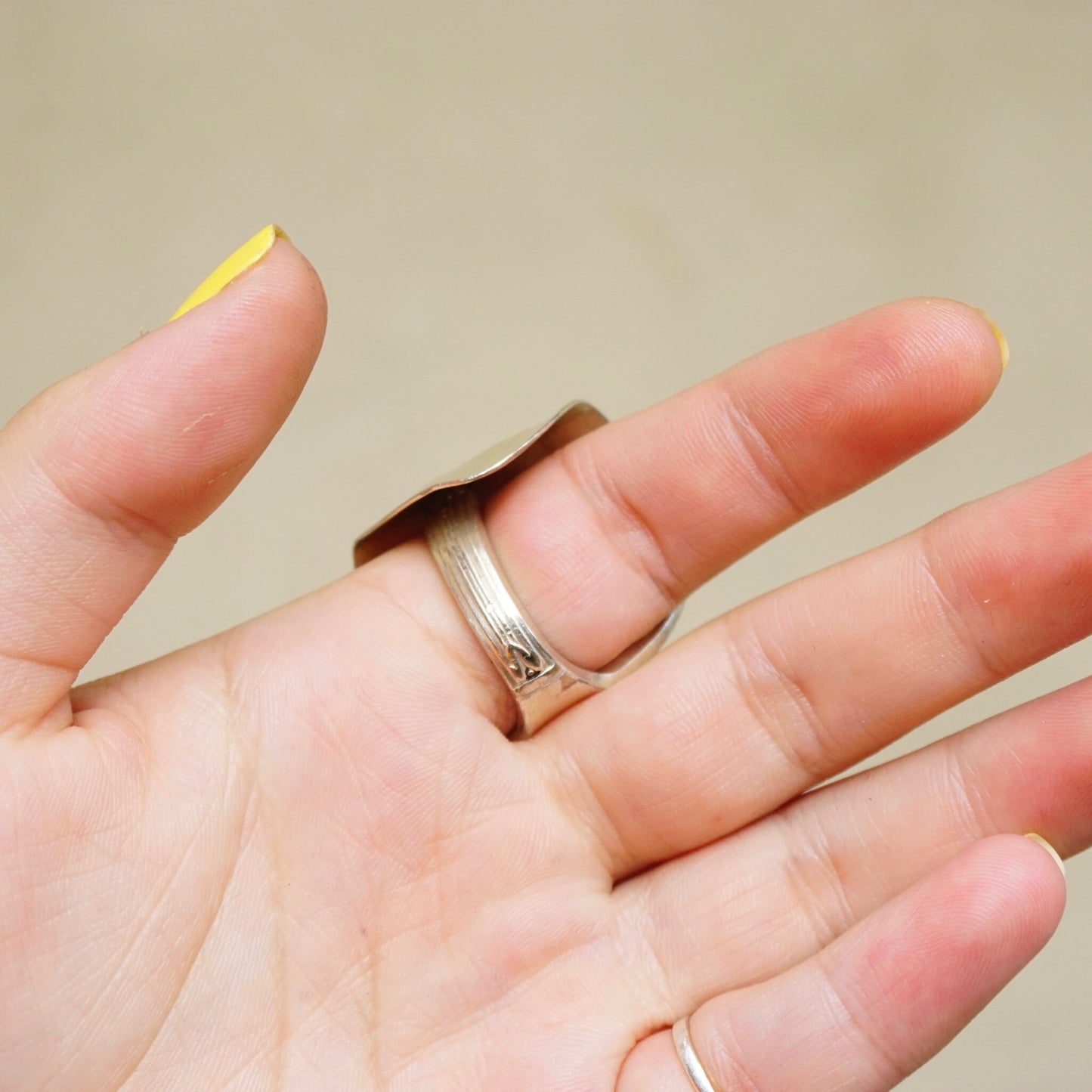 Vintage sterling silver spoon ring handcrafted into a unique, bent statement ring, shown on a hand against a plain background. Size 8 US ring.