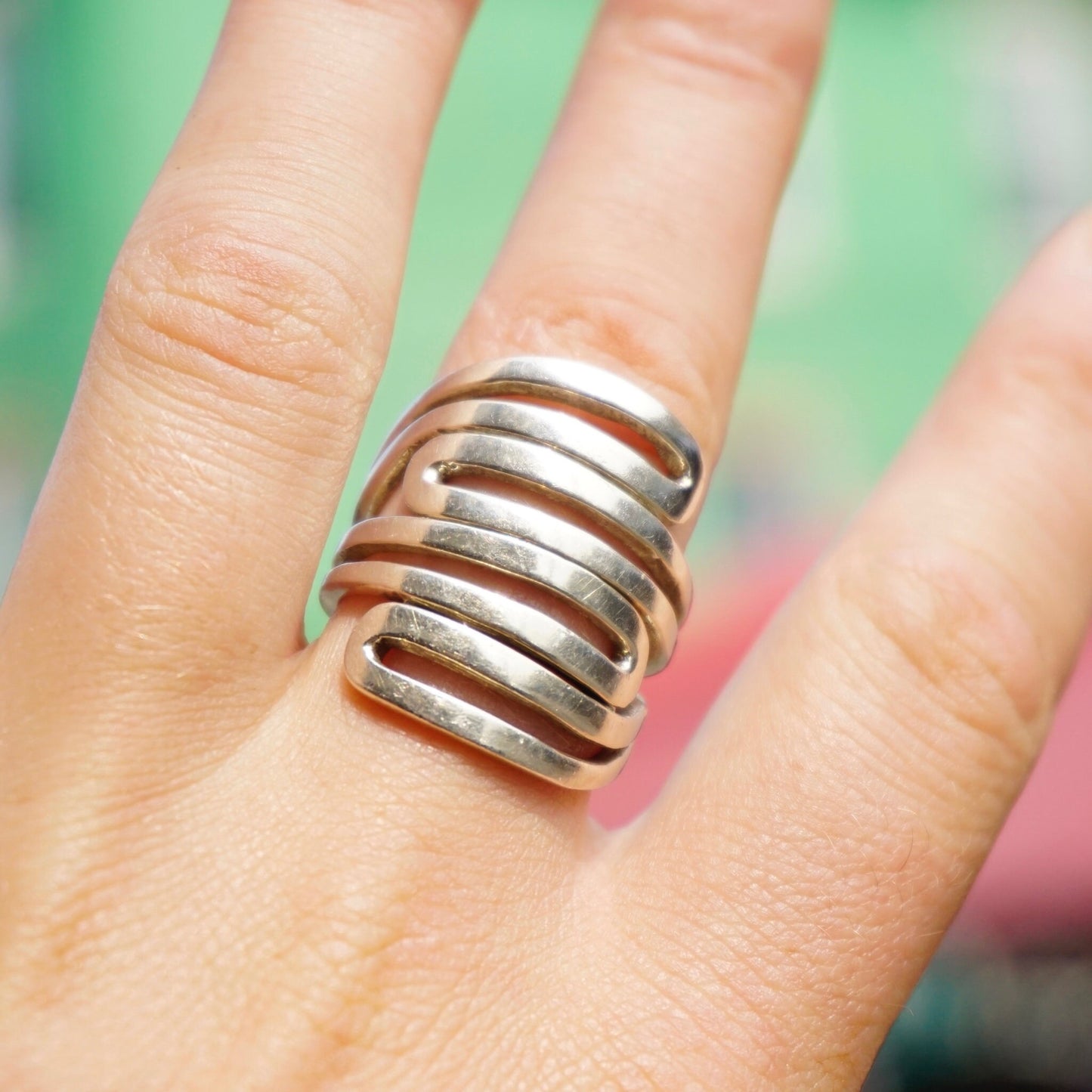 Vintage sterling silver cut-out statement ring made in India, shown on a hand against a colorful background.