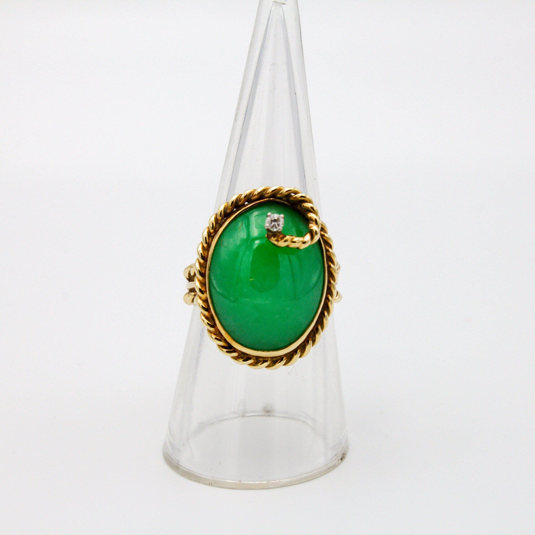 Vintage 14K gold cocktail ring featuring a large oval green jade stone cabochon, accented by a single round brilliant cut diamond, set in a twisted gold rope design mounting.