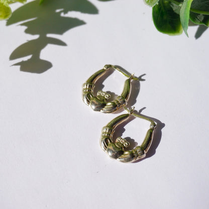 Vintage Sterling Silver Claddagh Hoop Earrings, Classic Irish Symbol Design, Representing Love Loyalty and Friendship, 925 Stamped Jewelry on White Background with Plant Shadows.