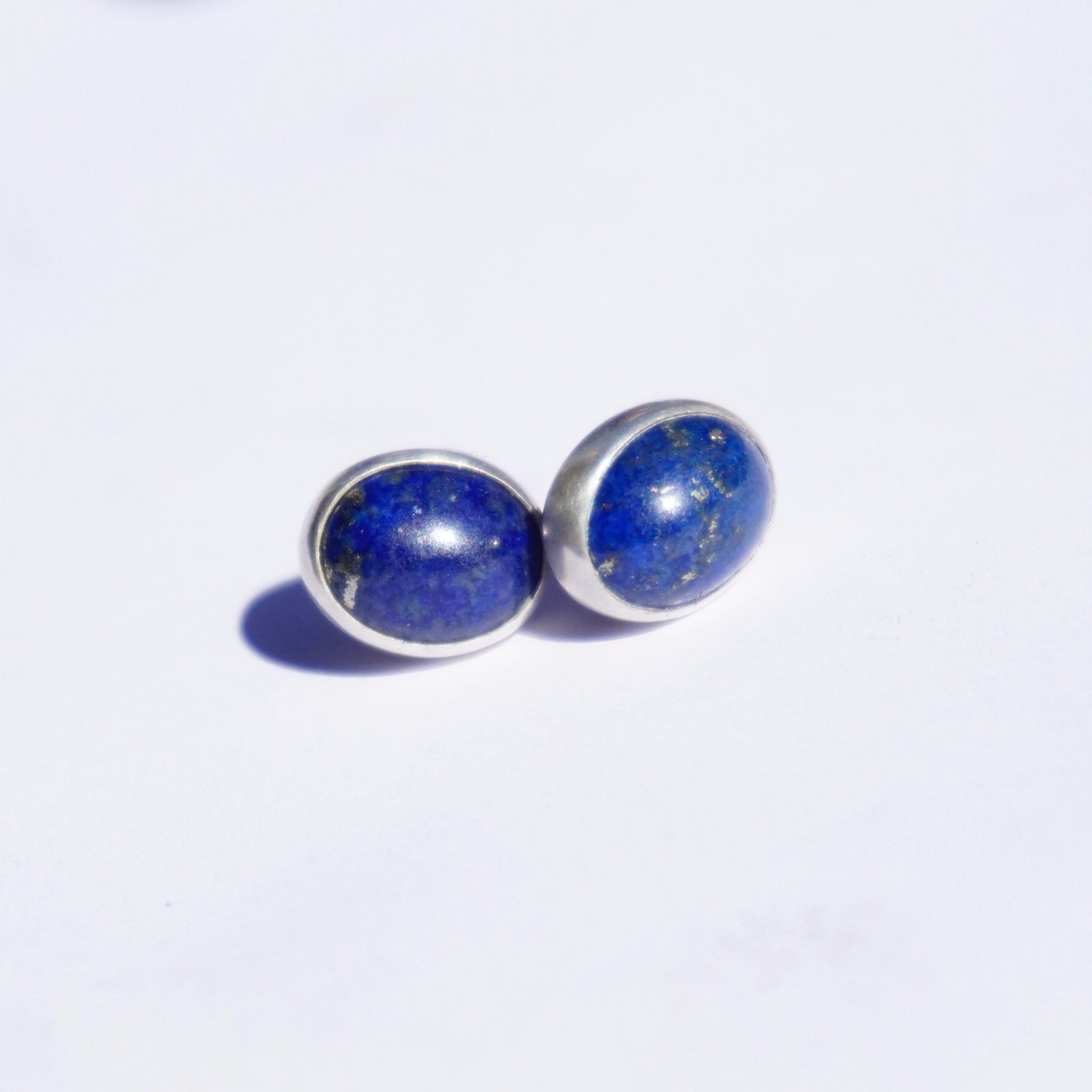 Vintage lapis lazuli stud earrings set in sterling silver on a white background, showcasing the deep blue color of the gemstones in a minimalist design.