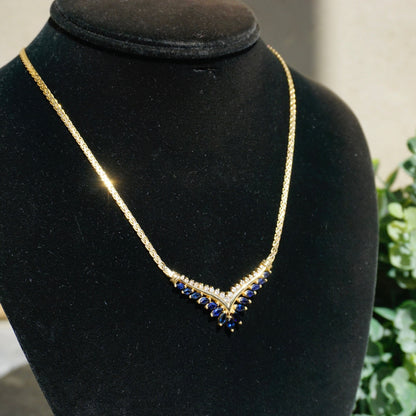 Elegant vintage 14k gold choker necklace featuring a V-shaped design with alternating round-cut sapphires and diamonds, displayed on a black velvet jewelry bust.