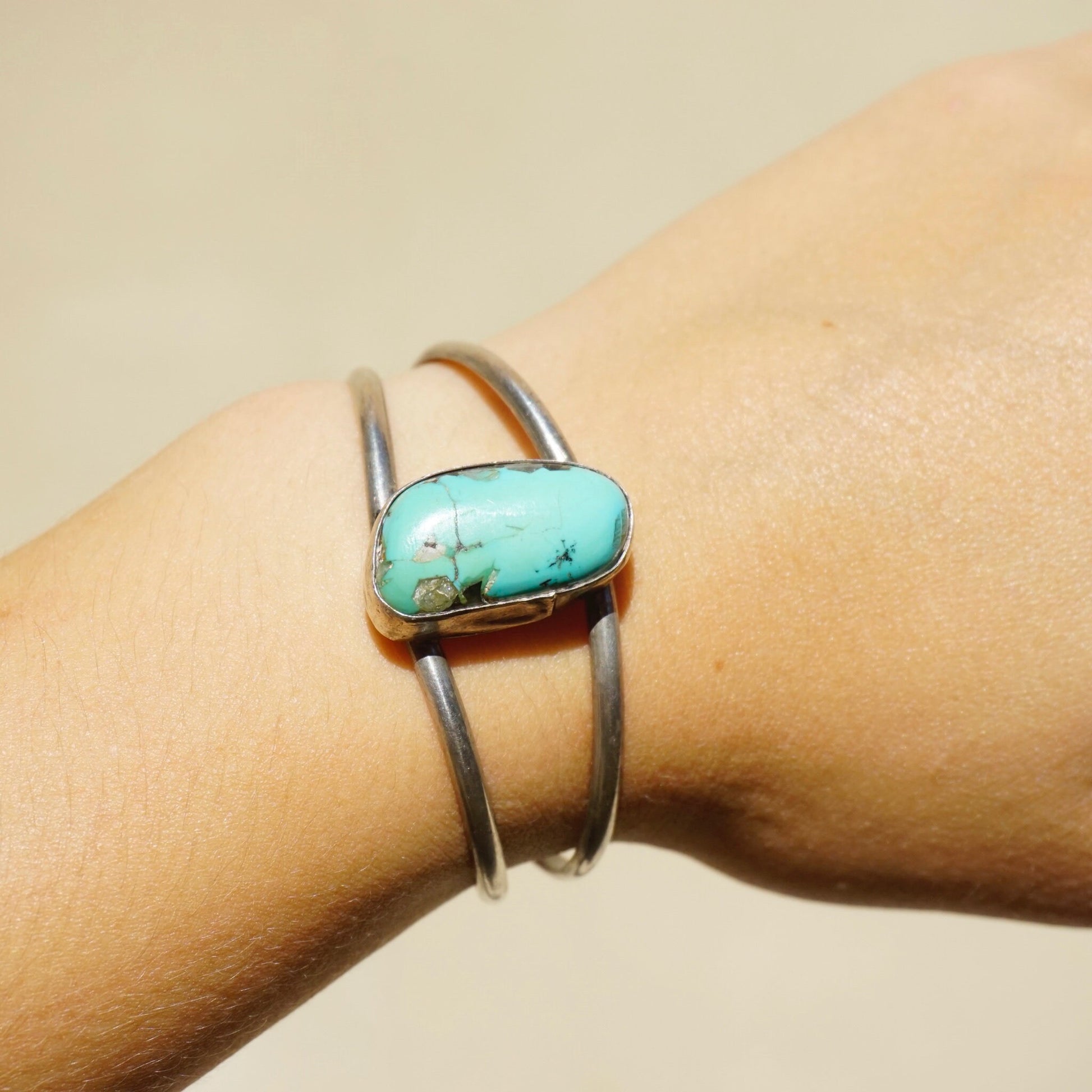 Vintage silver cuff bracelet with raised turquoise stone accent on a model's wrist